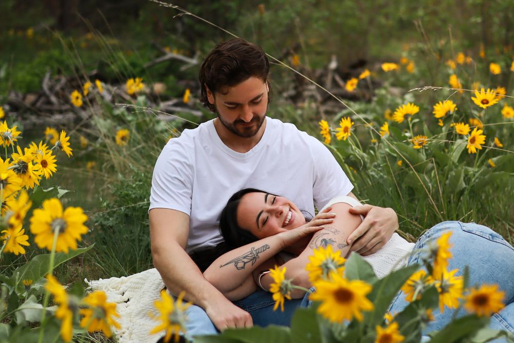 Couple lying in a field of blooming yellow wildflowers on a sunny afternoon.