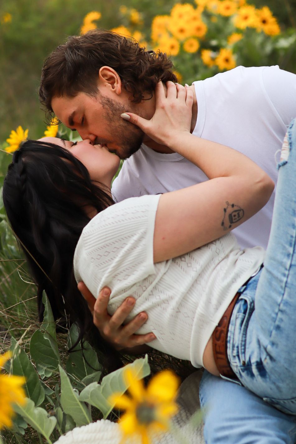 A romantic embrace set in a field of blooming yellow sunflowers on a sunny summer day.