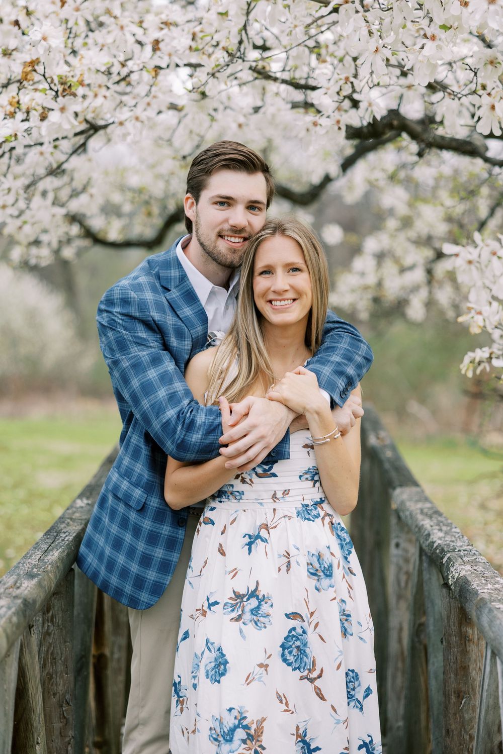 A romantic spring portrait under blooming cherry blossoms on a rustic wooden bridge in Warwick, New York.
