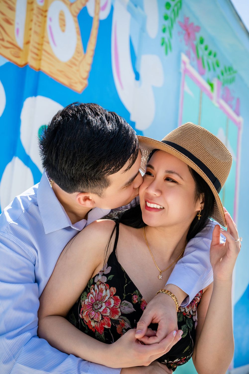 A couple shares an intimate moment against a colorful mural backdrop during their engagement photoshoot.