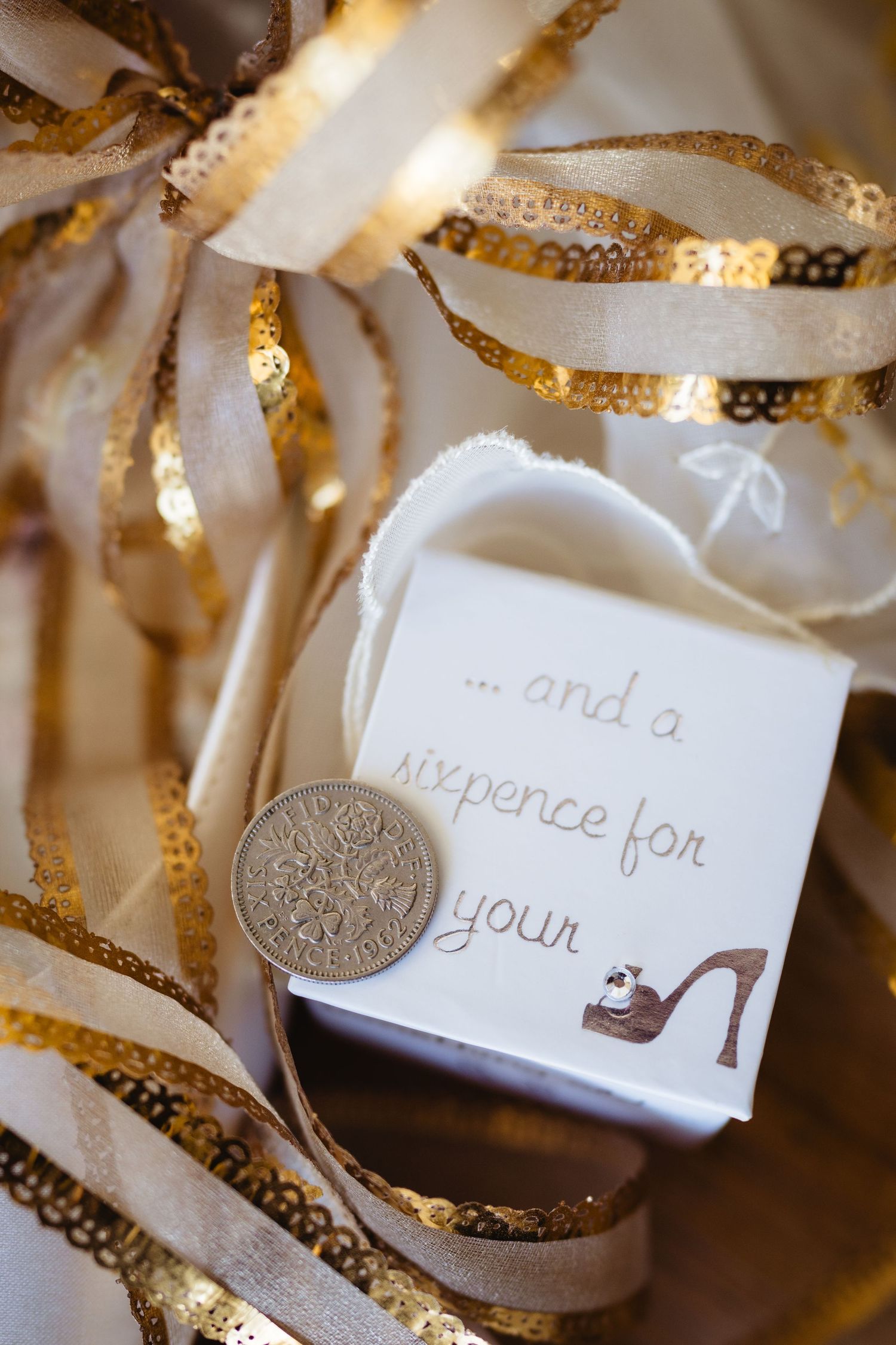 A silver sixpence coin and note beside gold and white ribbons symbolizing a bridal tradition.
