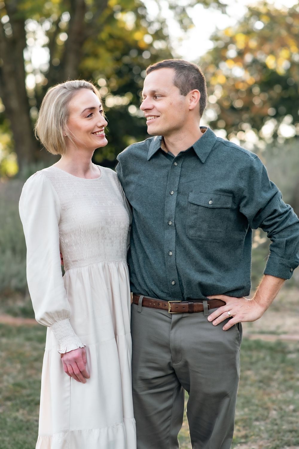 A couple in coordinating outfits sharing a tender moment outdoors during golden hour.