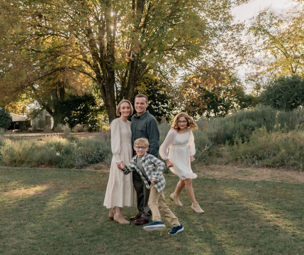 Family portrait in a park with natural lighting and autumn trees in the background.