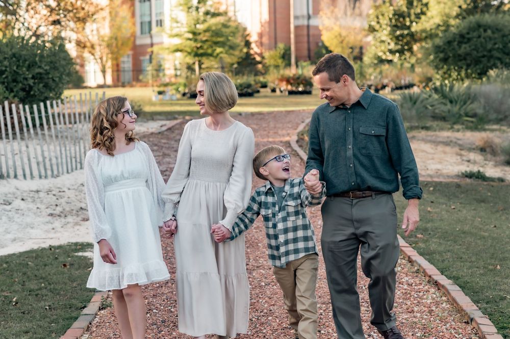 Family walking together on a garden path during an autumn photo session.