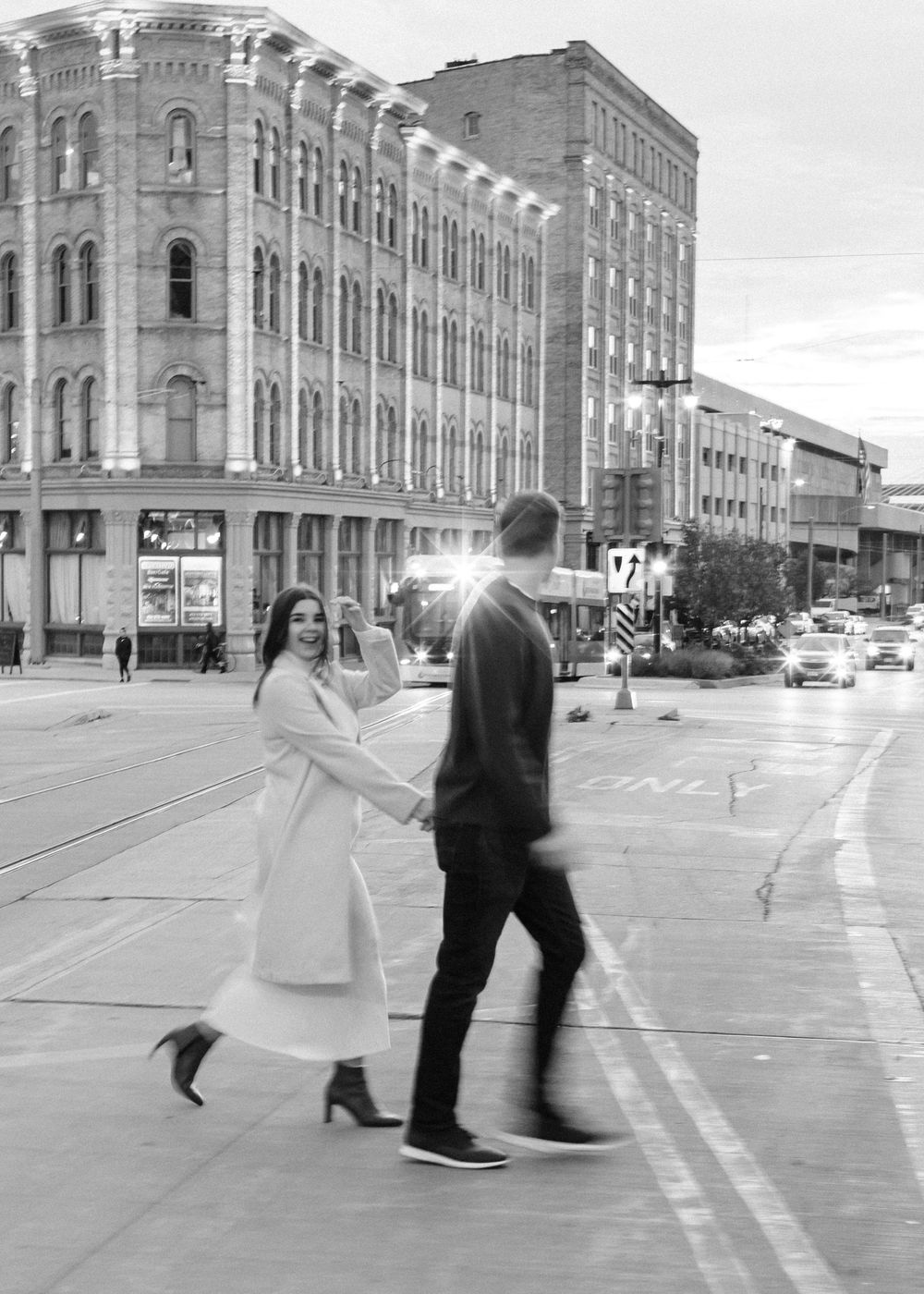 Black and white candid of couple crossing the street during an engagement session in Milwaukee