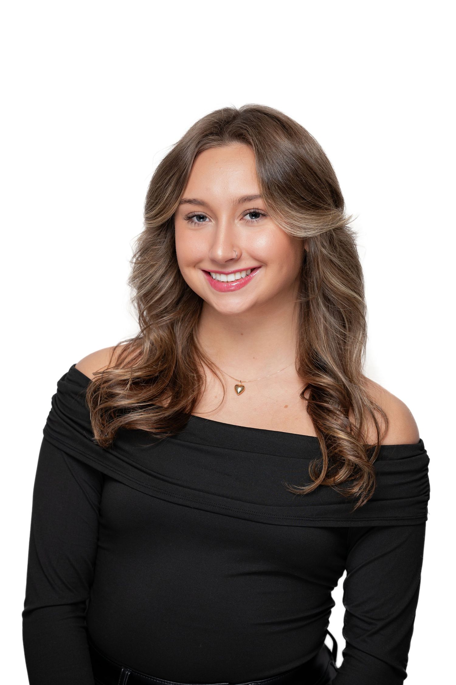 Professional studio portrait showing person in black off-shoulder top with wavy brown hair and delicate necklace.