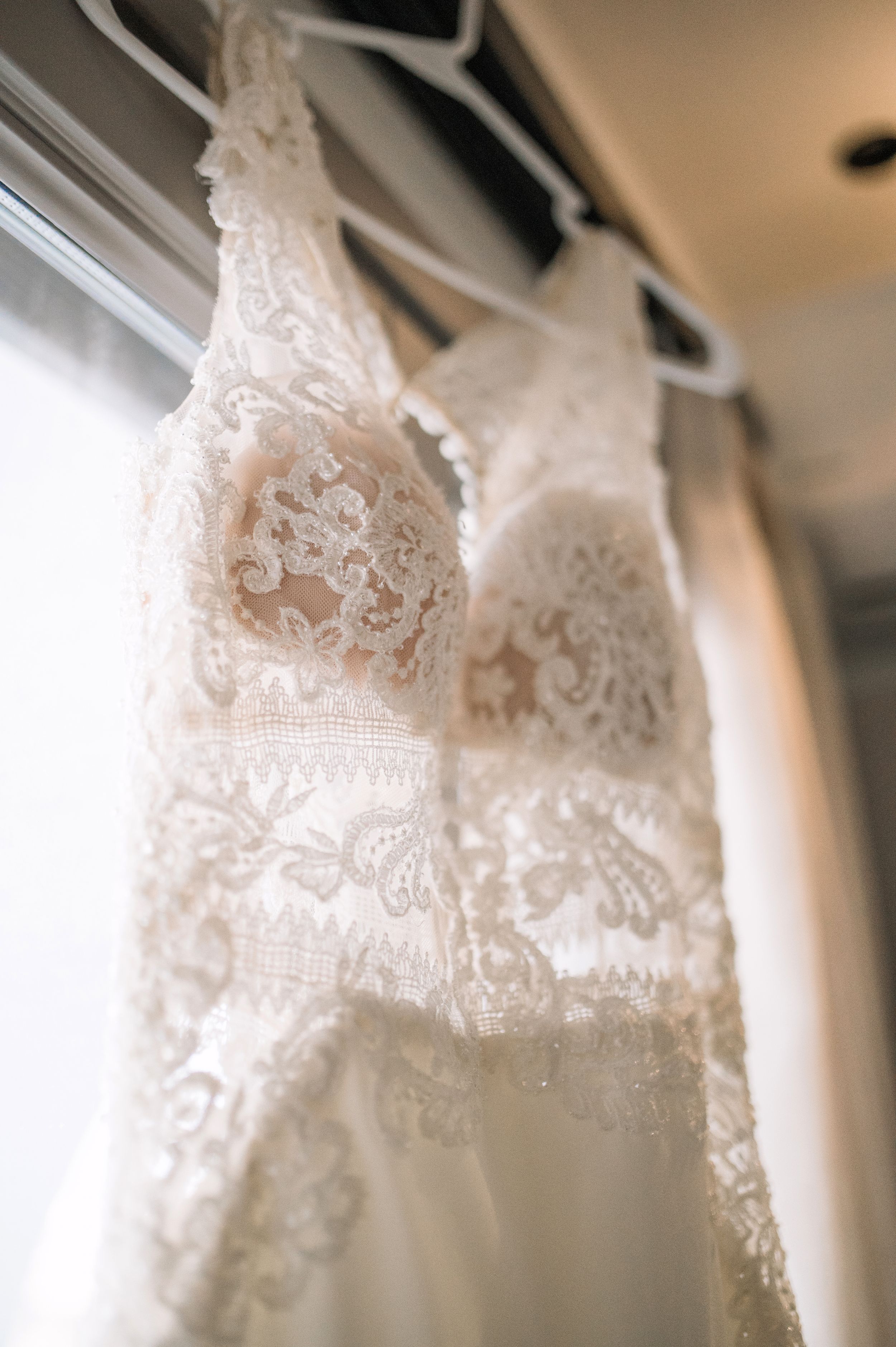 Close-up detail of an elegant lace wedding dress hanging on display.