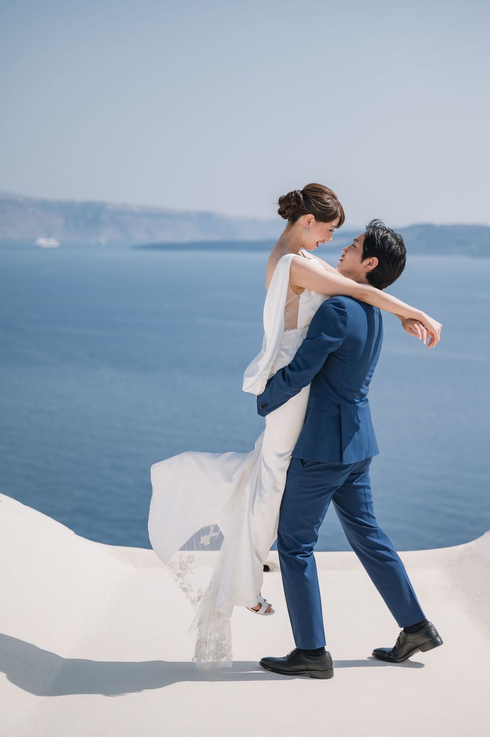 A couple dancing on white painted terraces with the blue Mediterranean Sea in background.