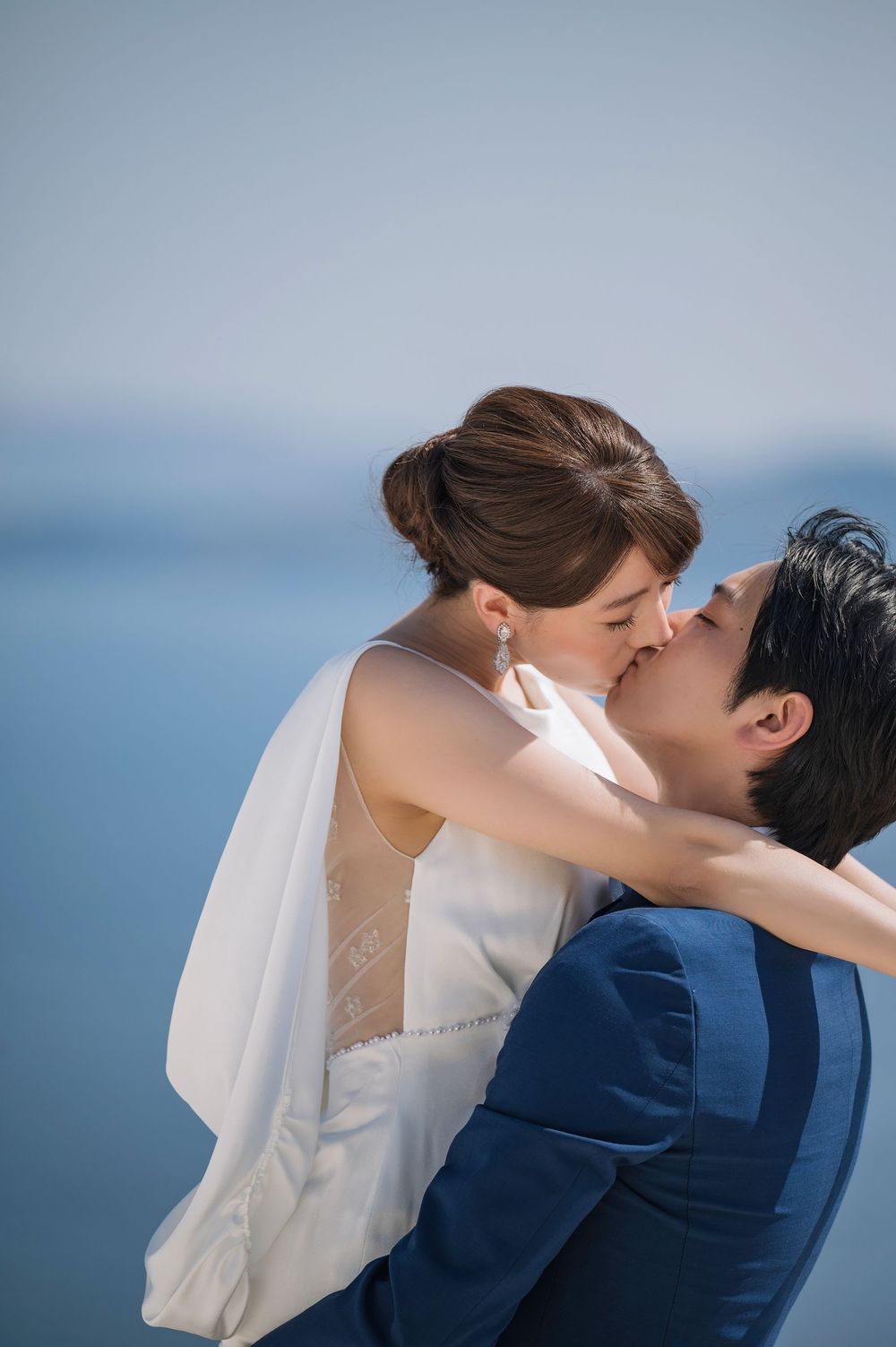 An intimate embrace captured against the backdrop of blue Mediterranean waters.