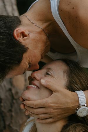 A couple shares a tender moment, man gently holding woman's face as she smiles up at him warmly.