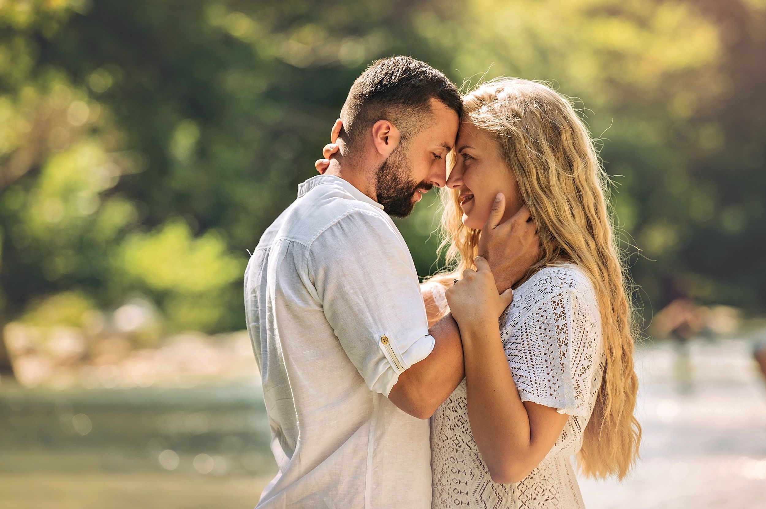 Intimate moment between couple touching foreheads during riverside photoshoot.