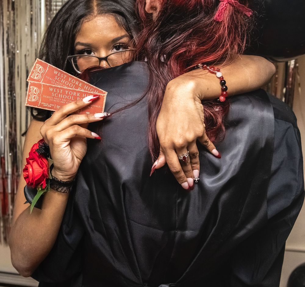 Someone holds up red tickets while posing in formal black attire with decorative backdrop.