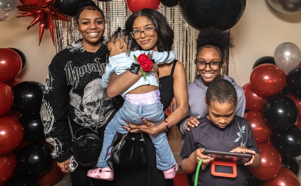 Family gathering with black and red balloon decorations and party atmosphere showing joyful people enjoying time together.