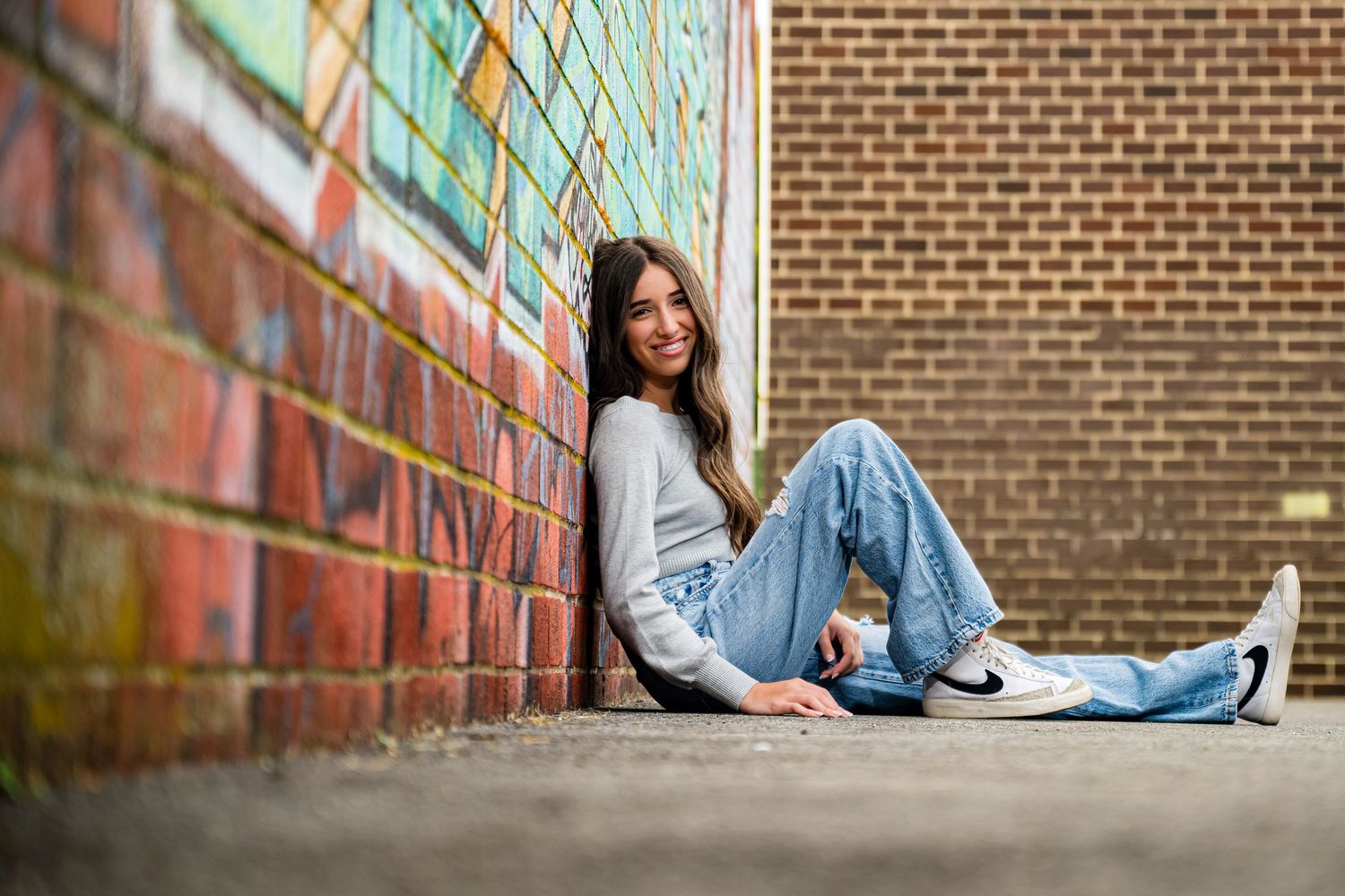 A series of senior portrait photos taken against a brick wall with colorful graffiti artwork.