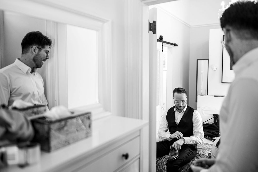 Black and white candid photo showing a group getting ready in a bright interior room with natural window light.
