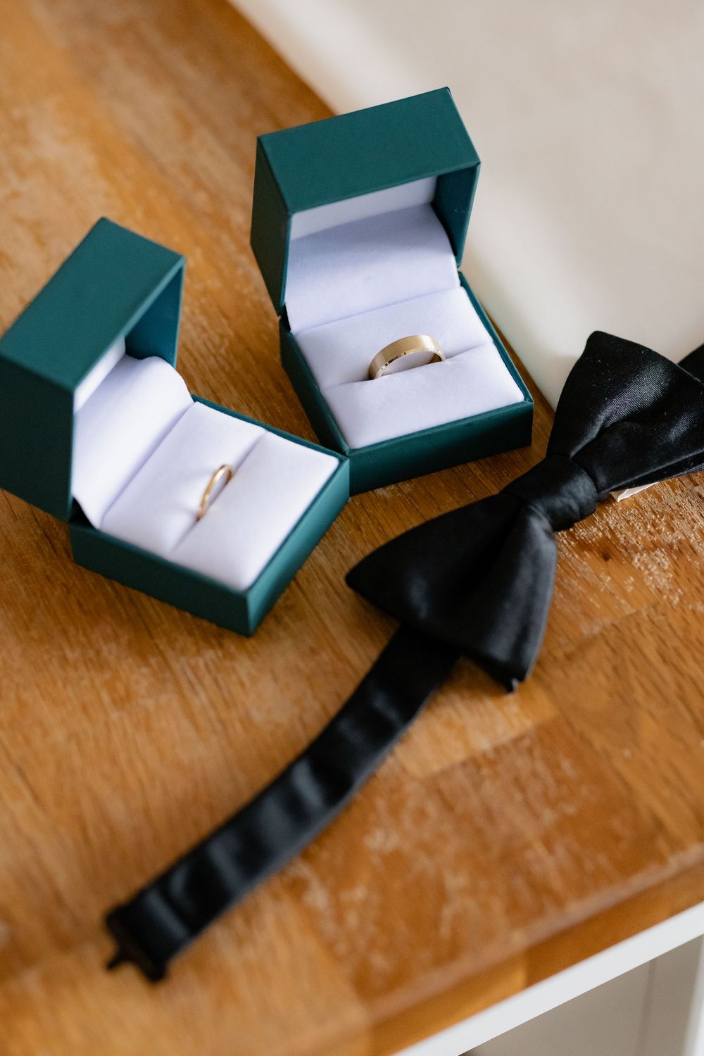 Green ring box with black ribbon shown in sequence on wooden surface, displaying jewelry presentation setup.