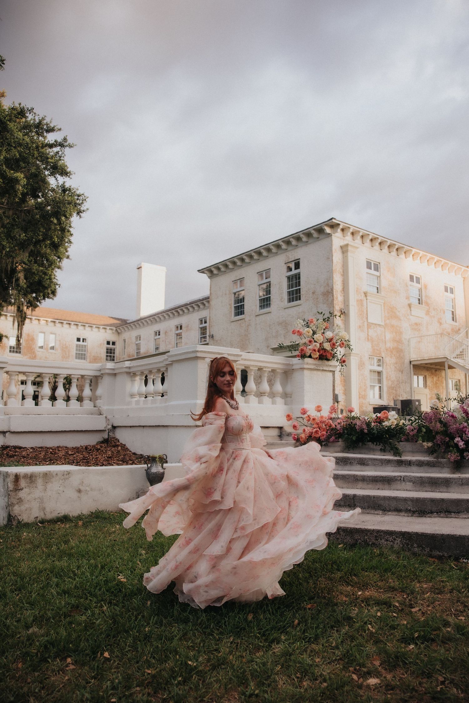 A series of outdoor steps with white railings and Spanish moss hanging from trees above creates a romantic garden setting.