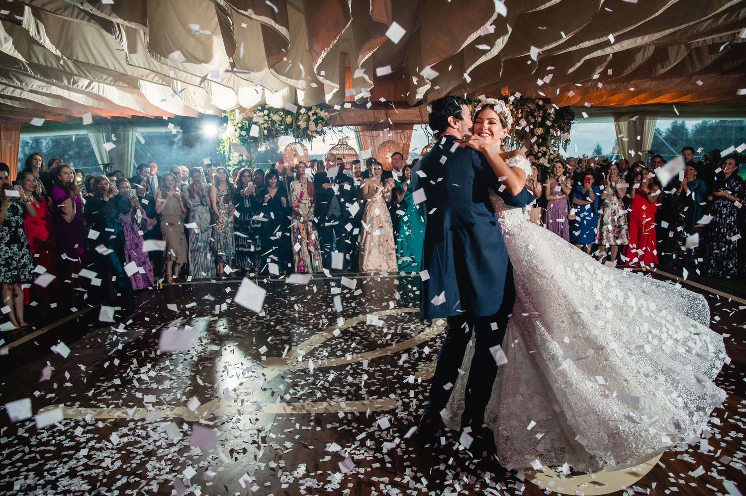 Confetti fills the air during a celebratory moment at an indoor wedding reception.