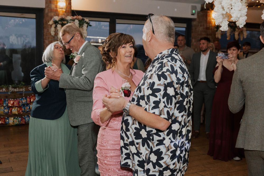 Wedding guests enjoy dancing together during a lively wedding reception celebration.