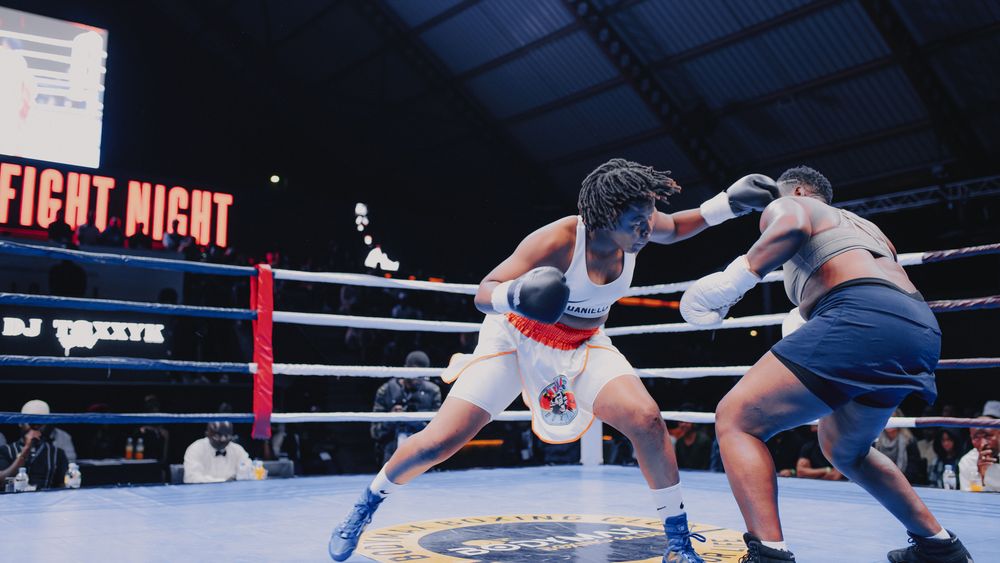 A boxer delivers a powerful strike to their opponent during a professional boxing match.