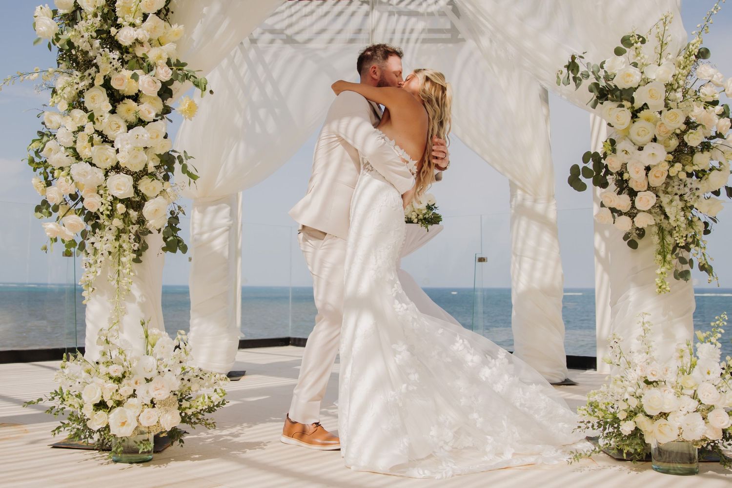 Elegant beach wedding ceremony setup with white floral arch and flowing Dreams Sapphire Riviera Maya Wedding Photography