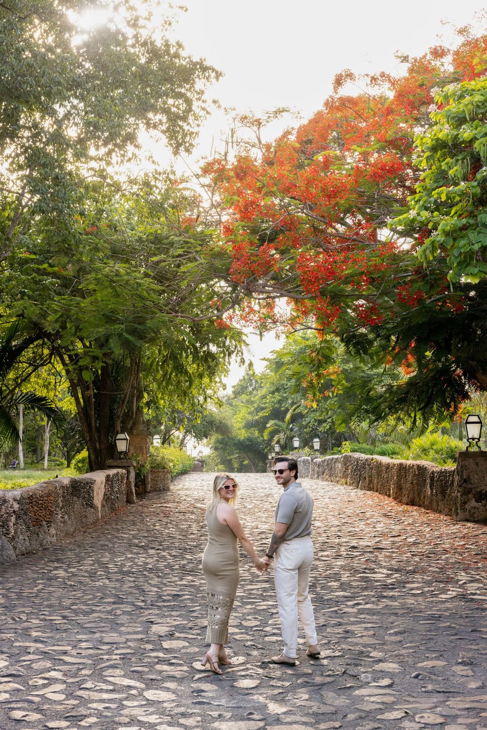 A cobblestone pathway surrounded by autumn trees with red foliage creates a romantic scene in a park.