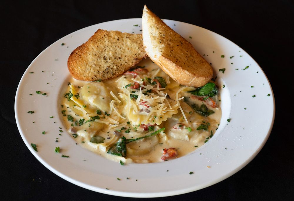 A creamy seafood chowder served in a white bowl with toasted bread and garnished with fresh herbs.