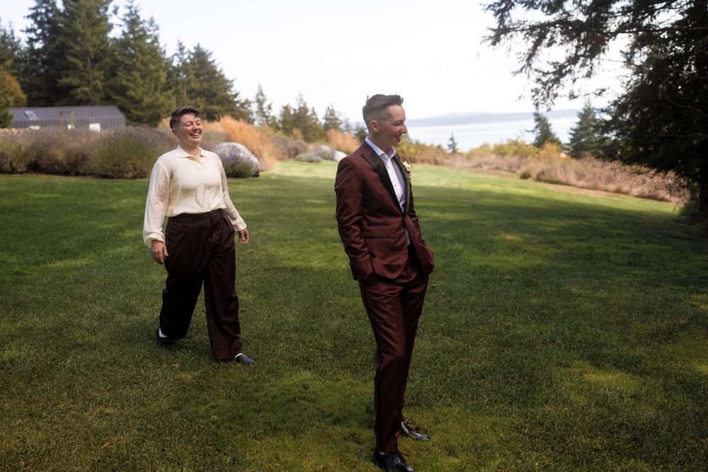 Two people walking together on a grassy hillside during golden hour.