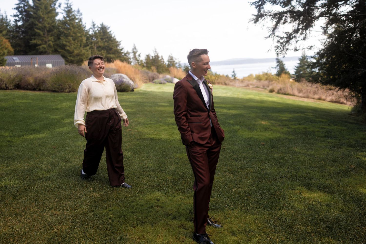 Two people walking together on a grassy hillside during golden hour.
