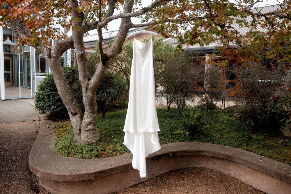 White chairs arranged in rows on a grassy lawn surrounded by autumn trees for an outdoor wedding ceremony.