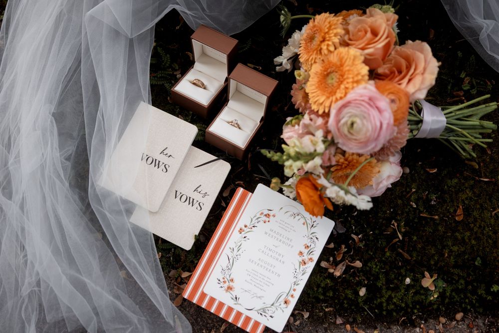 Wedding stationery and peach-colored roses arranged artistically with tulle fabric.