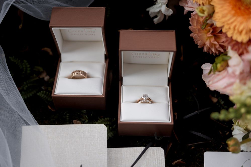 Close-up shots of an engagement ring in multiple open jewelry boxes with flowers in the background.