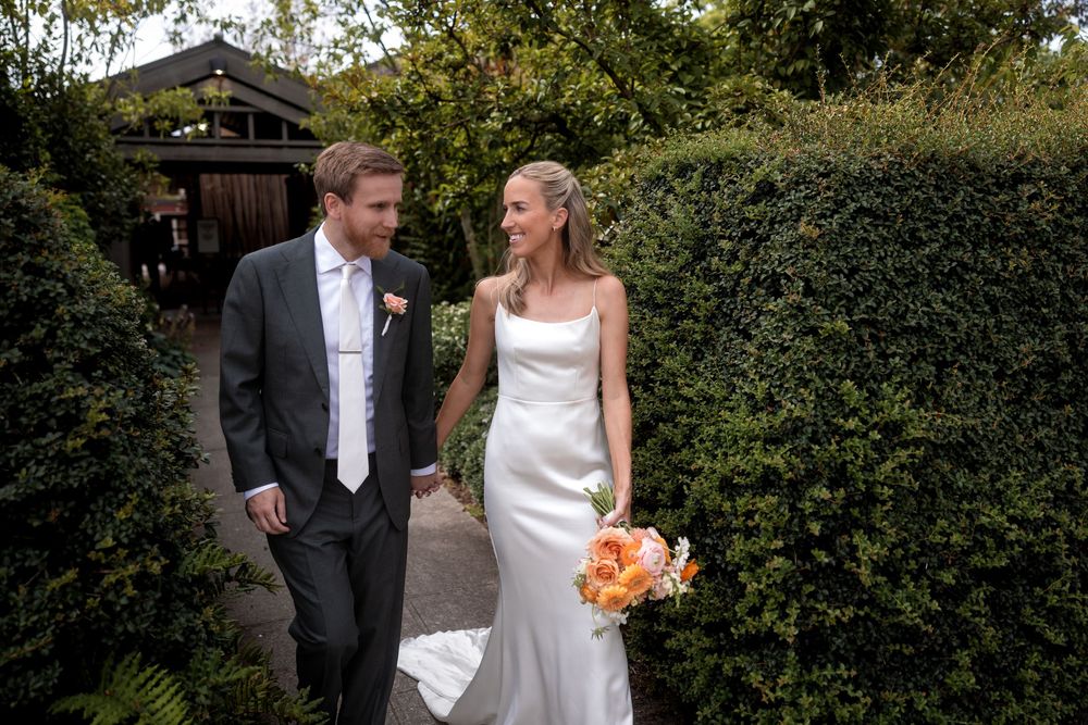 Wedding couple and party members posing for portraits in a lush garden setting.