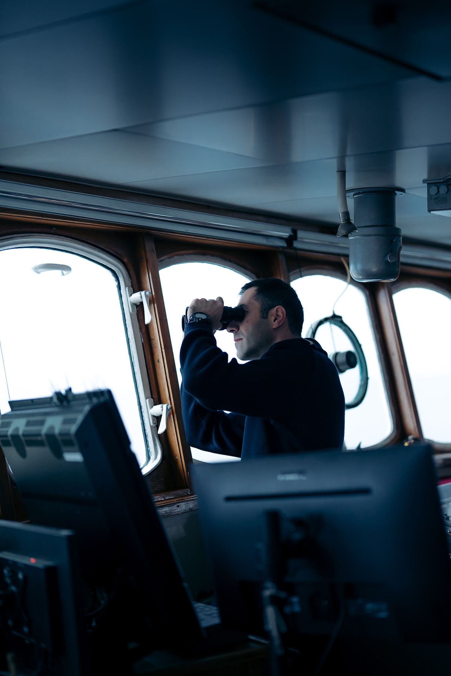 commandant du bateua polarfront qui regarde dans ses jumelles à travers le hublot