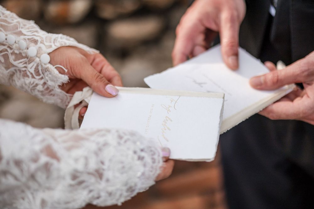 A close-up view of hands holding a white lace wedding dress fabric being adjusted and prepared.