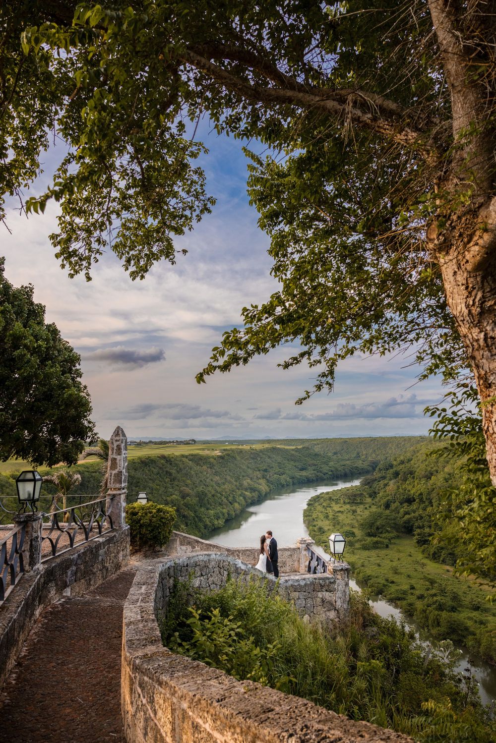 Scenic overlook of a winding river valley from a stone fortress wall with trees and cloudy skies in Chauvigny, France.