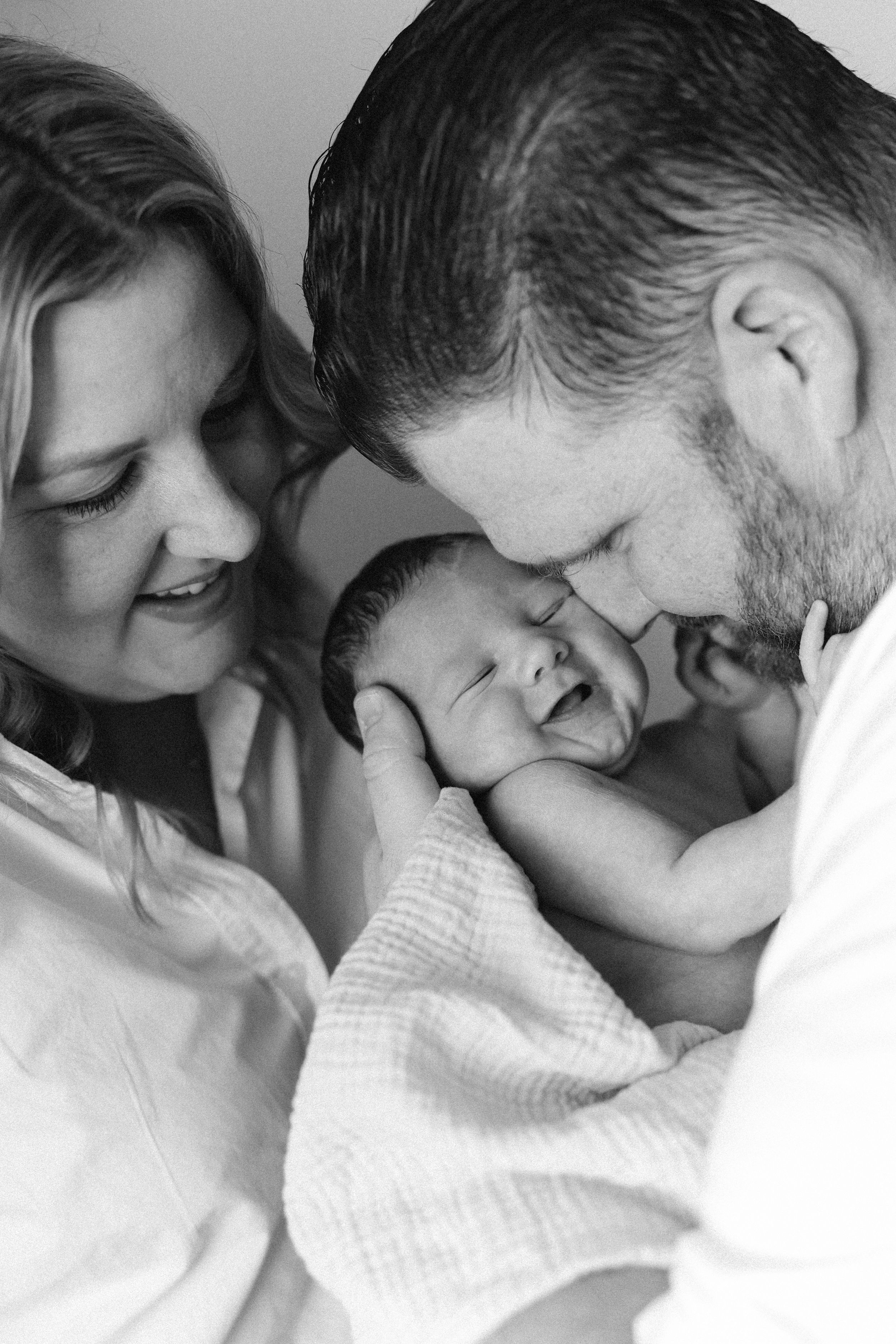 Newborn photos of baby and parents cuddling and showing soft features in a California studio