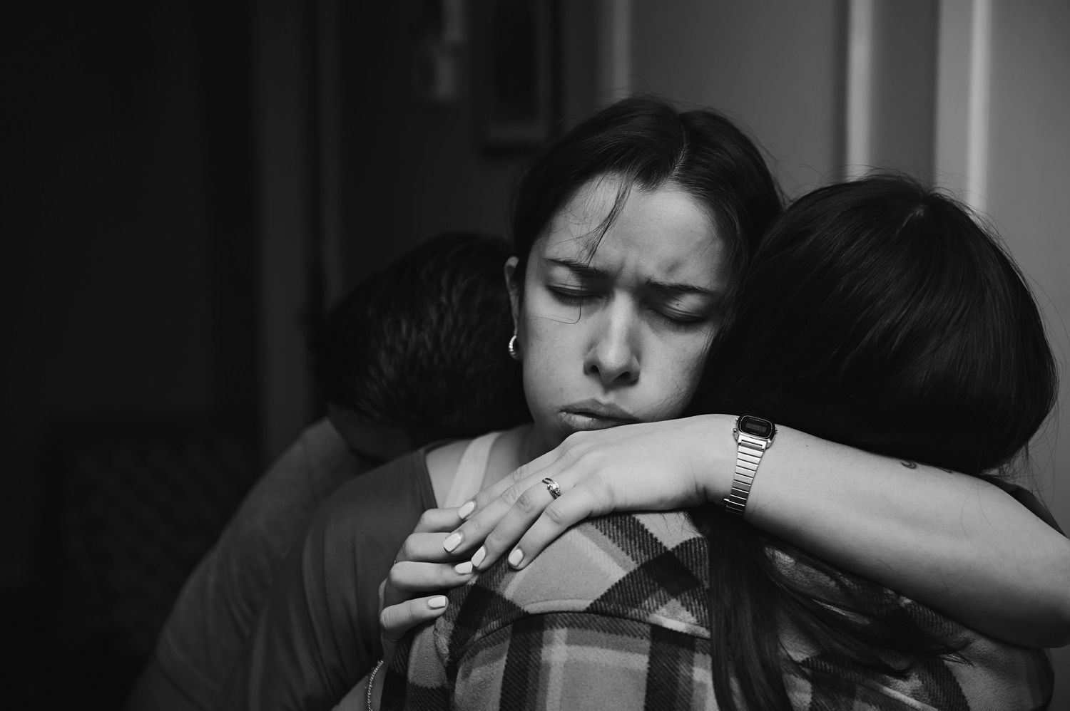 Black and white photo showing two people embracing in an emotional moment, with one person's arm wrapped around the other during labor.