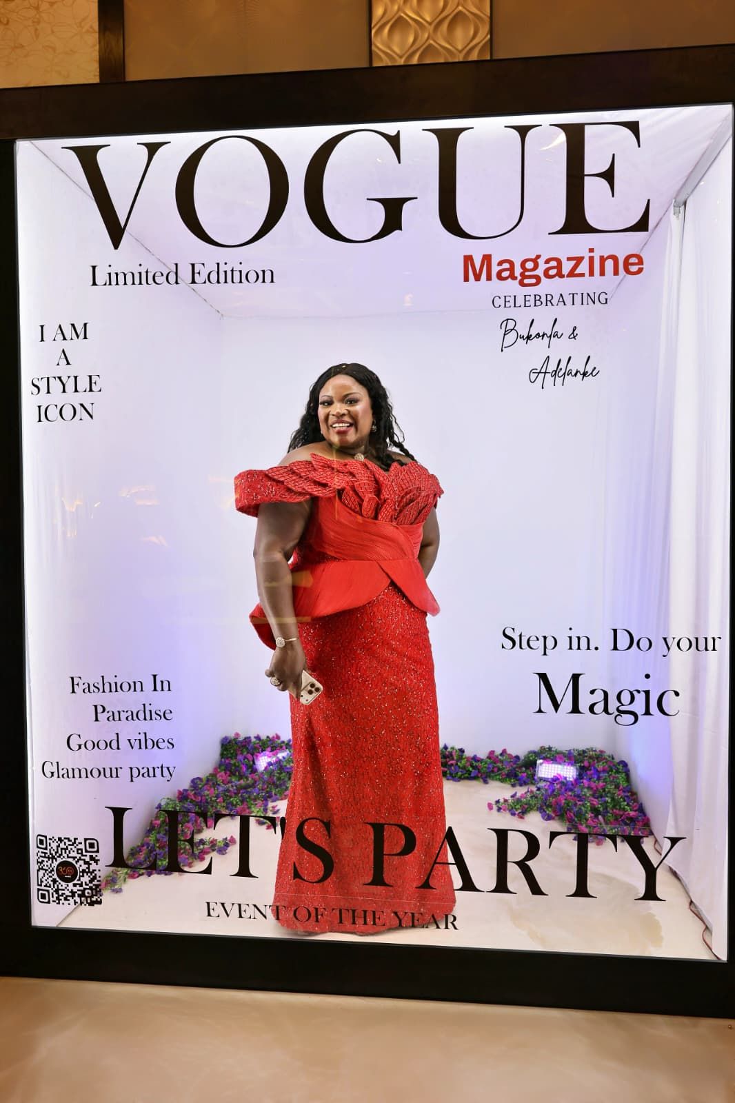 Woman in stunning red lace gown posing inside a Vogue Magazine Limited Edition party photo booth.