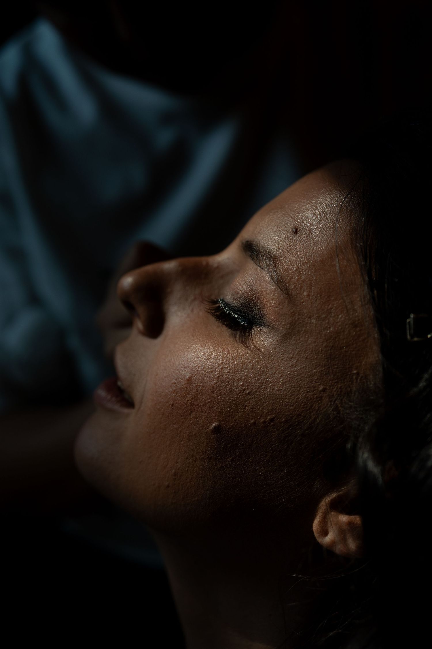 Dramatic close-up profile portrait with moody lighting and dark shadows creating an artistic atmosphere.