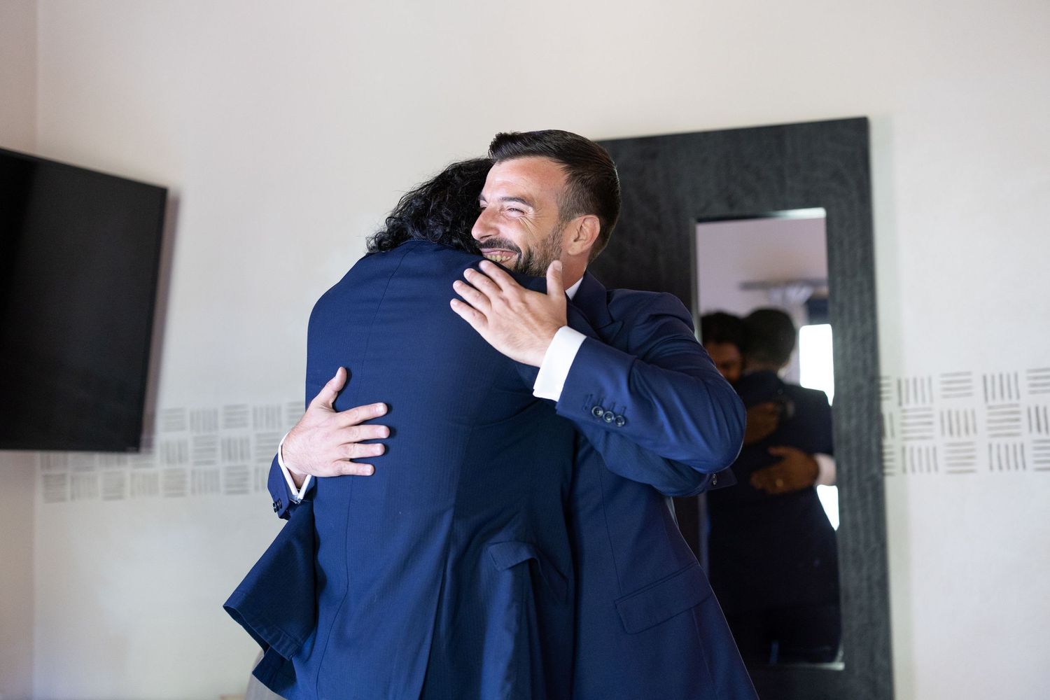 Two people sharing an emotional embrace in an office hallway.
