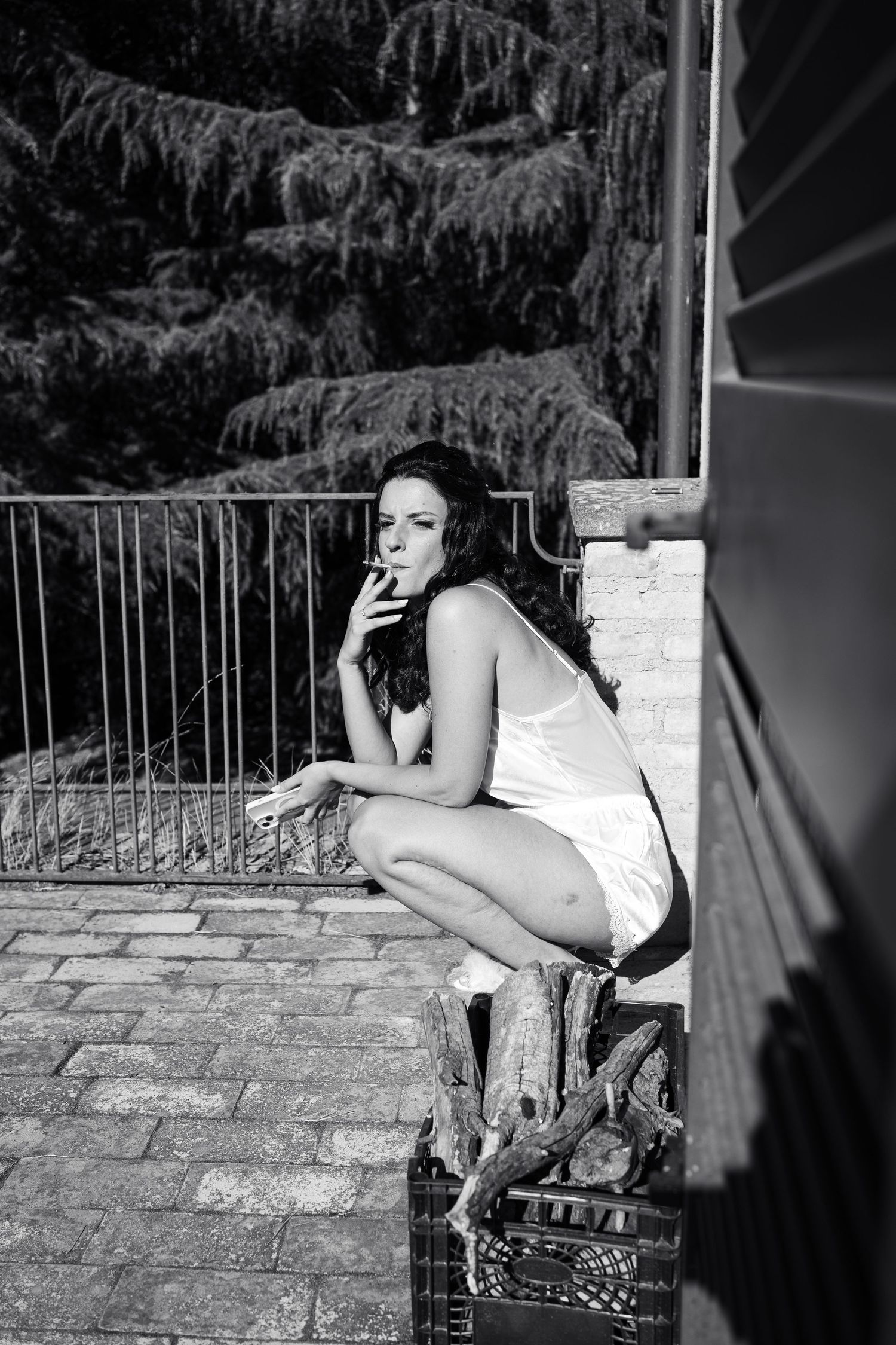 Artistic black and white portrait session on stone balcony with dramatic lighting.
