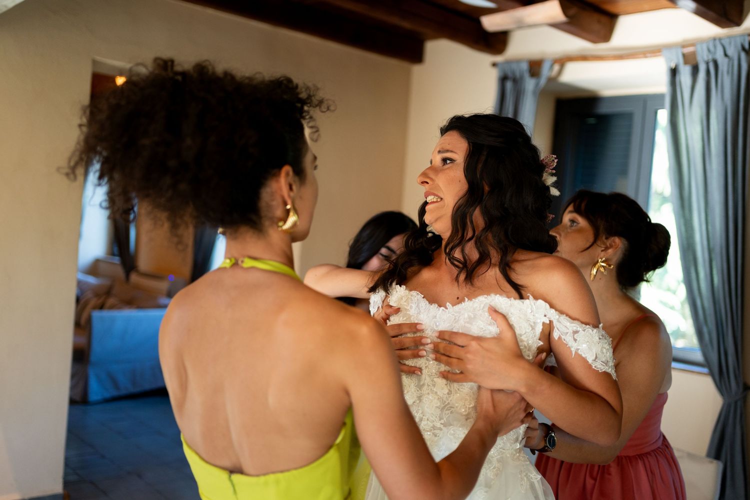 Joyful bridesmaids in colorful dresses sharing an emotional moment during wedding preparations.