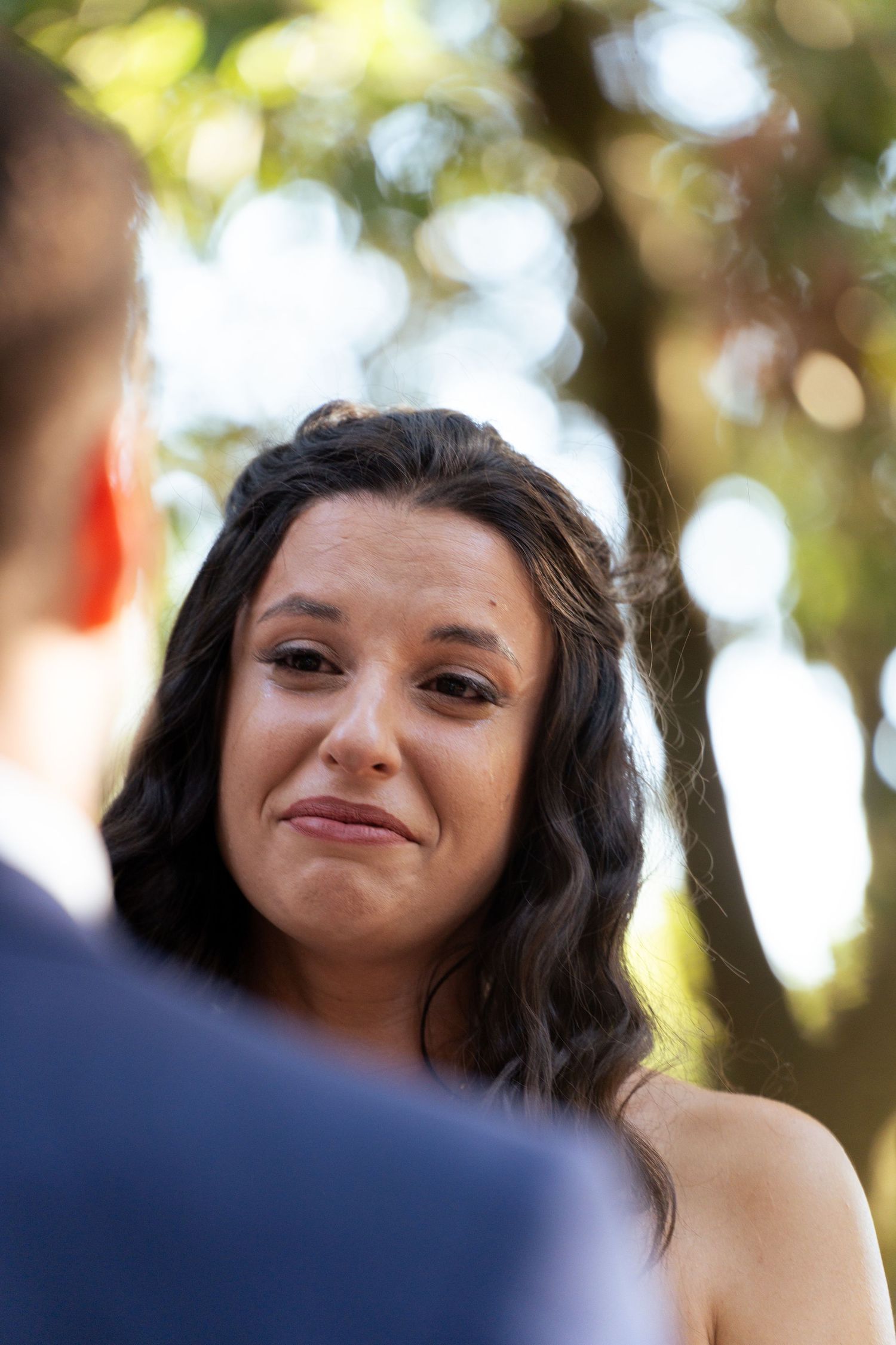 An emotional moment captured during a wedding ceremony outdoors with natural bokeh lighting.