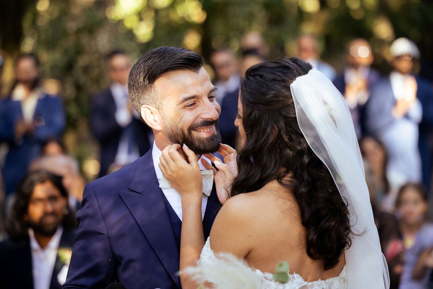 Wedding ceremony in a sunlit outdoor setting with white fabric decorations.