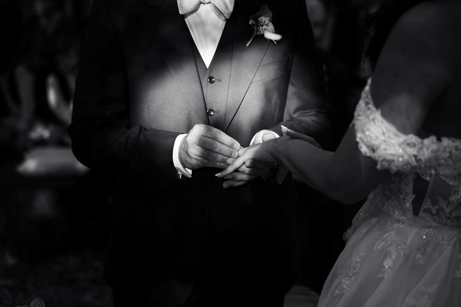 Black and white artistic photo showing wedding dress details in dramatic lighting.