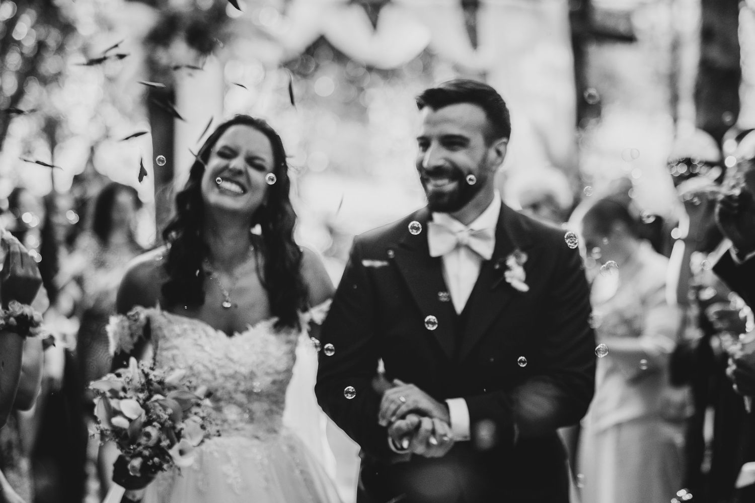 A joyful black and white wedding scene with people celebrating and laughing together outdoors.