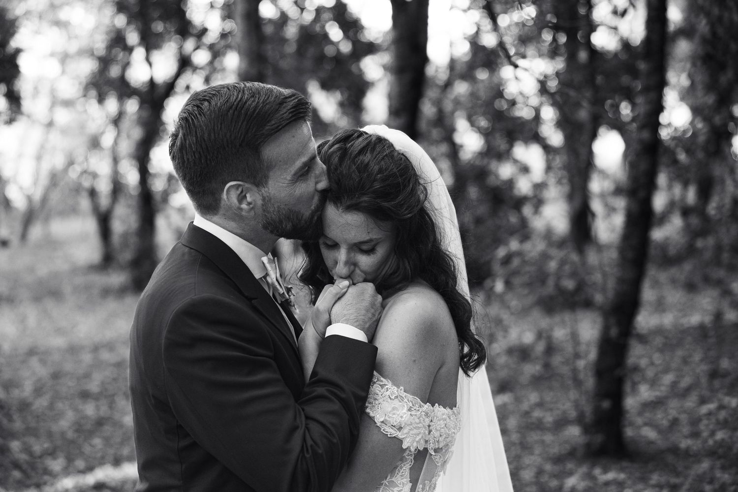Black and white romantic wedding portrait among trees with natural lighting.