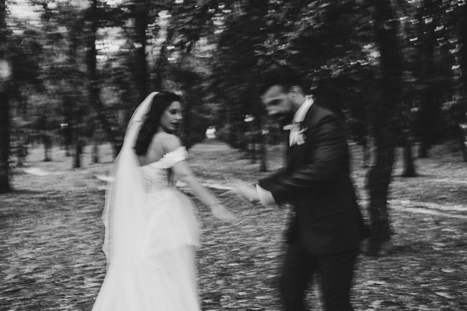 Couple walks hand in hand through a wooded outdoor wedding venue.