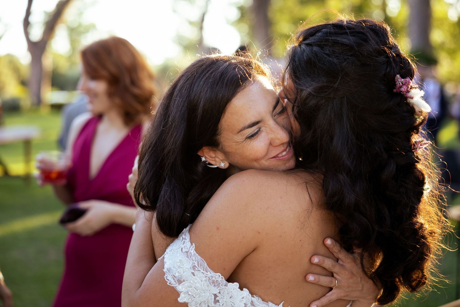 Joyful wedding celebration scene with warm sunlight filtering through trees in an outdoor setting.